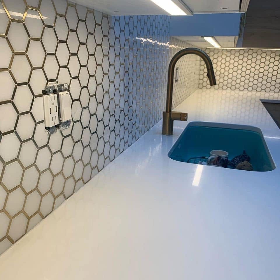 White hexagon mosaic backsplash with gold grout and brass fixtures