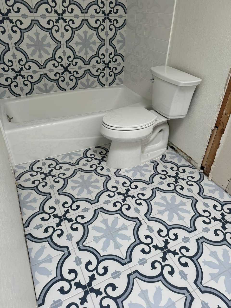Bathroom with bold blue and white patterned cement-look tile on floor and tub surround