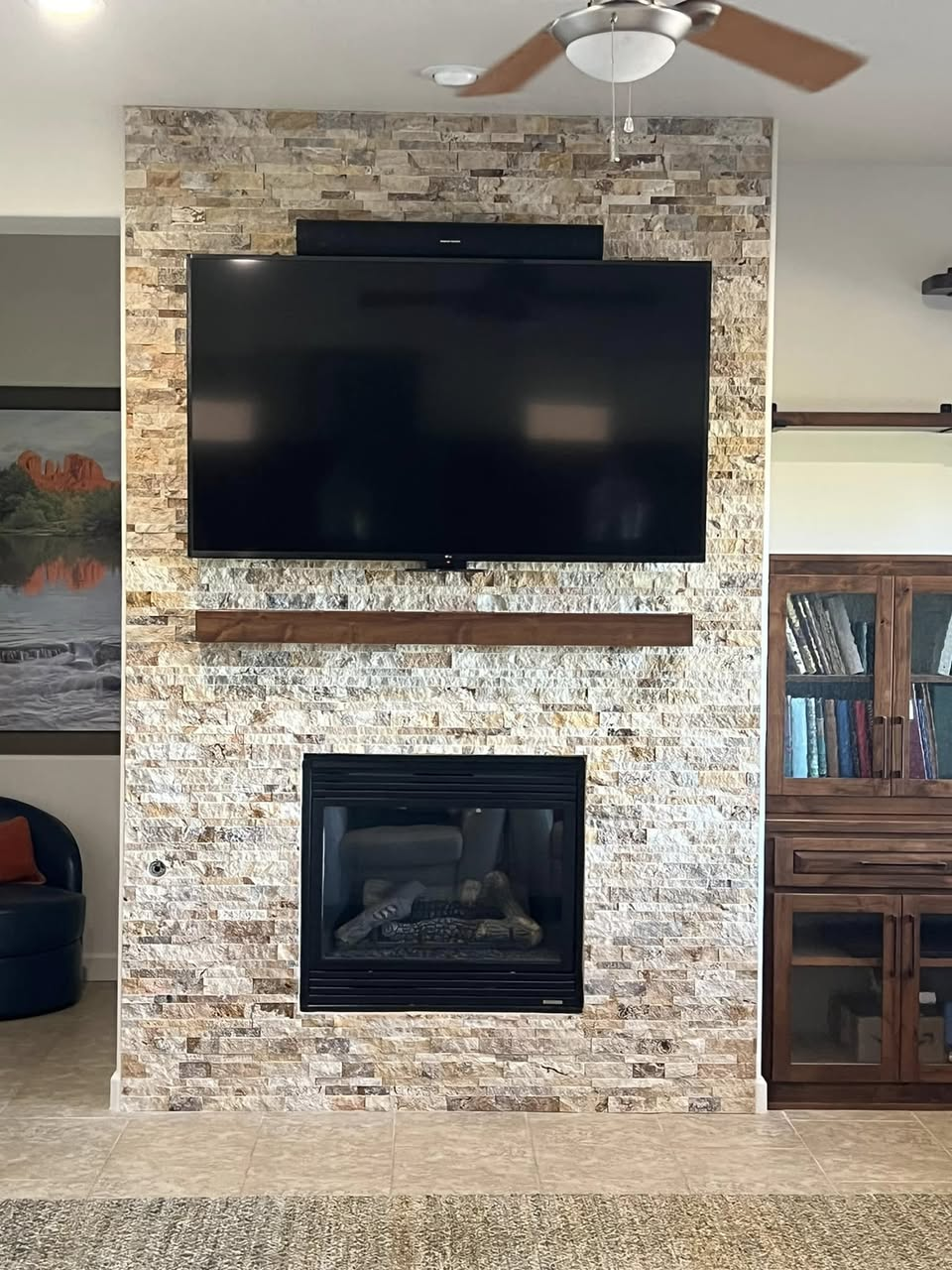 Floor-to-ceiling stacked stone fireplace feature wall with mounted TV