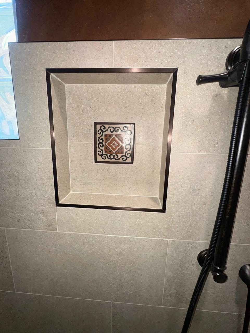 Recessed shower niche framed in bronze with decorative Talavera accent tile
